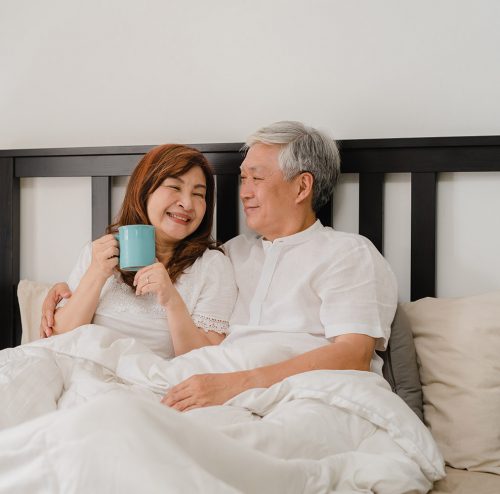 Asian senior couple talking on bed at home. Asian Senior Chinese